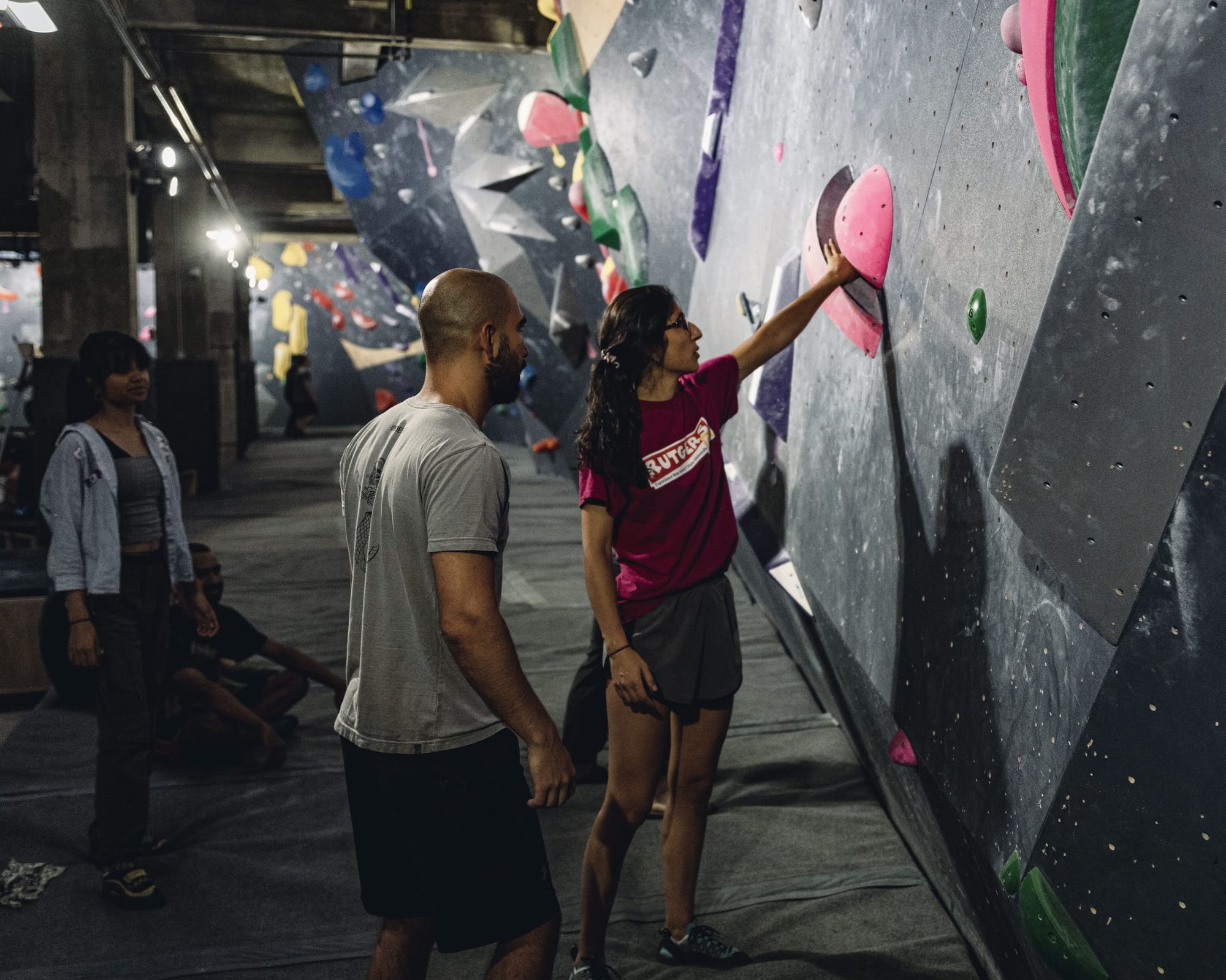 Three climbers silhouetted against the bouldering wall